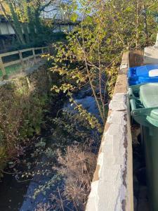 a small stream of water next to a fence at Kingfisher Cottage in High Bentham