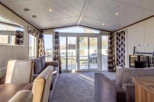 a living room with couches and a table and windows at Luxury Caravan Nearby The Beautiful Scratby Beach In Norfolk Ref 50001a in Great Yarmouth