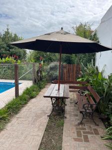 a picnic table with an umbrella next to a pool at El Descanso Casa de retiro in Tandil