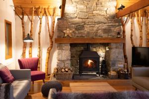 sala de estar con chimenea y pared de piedra en The Wilds - Seasgair Lodges en Kingussie