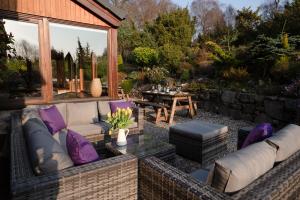 a patio with a couch and a table in a yard at The Wilds - Seasgair Lodges in Kingussie