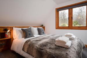 1 dormitorio con 1 cama grande y toallas. en The Wilds - Seasgair Lodges en Kingussie