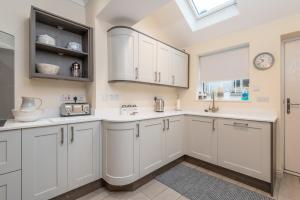 a kitchen with white cabinets and a window at Sleeps 6 4 bedrooms 2 minute walk to the Square Hosted Happy Valley Cast in Hebden Bridge