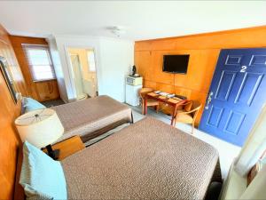 a hotel room with two beds and a blue door at Hillcrest Inn & Motel in Rapid River