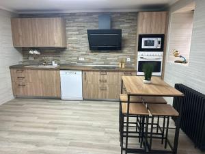 una cucina con mobili in legno, un tavolo e una TV di www luabierzo a Molinaseca