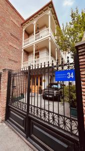 um portão em frente a uma casa com um sinal azul em Marmenio Hotel - Tbilisi em Tbilisi