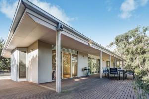 Casa con terraza grande con mesa y sillas en Acacia Lakehouse en Goon Nure