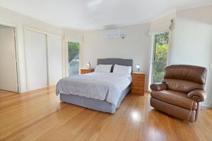 a bedroom with a bed and a leather chair at Acacia Lakehouse in Goon Nure
