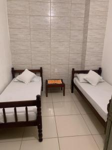 Habitación con 2 camas y mesa. en Hotel Pousada AngraAntiga, en Angra dos Reis