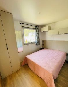 a small bedroom with a pink bed and a window at Camping de Parpaillon in Roquebrune-sur-Argens