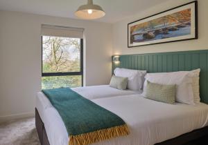 a bedroom with a large white bed with a window at The Mole Resort - Lodges in Chittlehamholt