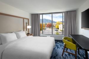 a hotel room with a bed and a desk and a window at Fairfield Inn & Suites Boulder in Boulder