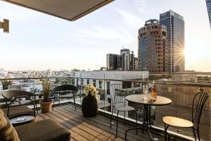a balcony with tables and chairs and a view of a city at Upscale Rotschild by Five Stay in Tel Aviv