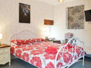 a bedroom with a bed with a red and white comforter at The Coach House in Blencogo