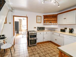 a kitchen with white cabinets and a stove top oven at 13 The Square in Oakamoor