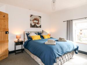 a bedroom with a blue bed with yellow pillows at 13 The Square in Oakamoor