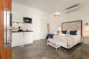 a white bedroom with a bed and a kitchen at Indulge en Sevilla Zaragoza in Seville