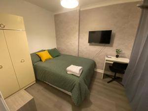 a bedroom with a bed and a desk and a television at Culbin Drive, Glasgow in Glasgow