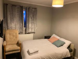 a bedroom with a bed and a chair and a window at Culbin Drive, Glasgow in Glasgow