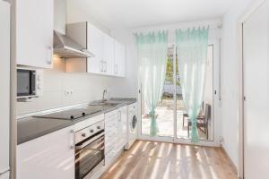 a kitchen with white cabinets and a large window at Villa Dimarts- a 100m de playa in Gandía