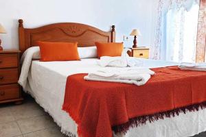 a bed with orange pillows and a red blanket at Apartamento Jarmar Puerto Santiago in Puerto de Santiago
