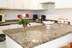 a kitchen counter with a vase with roses in it at Apartamento Jarmar Puerto Santiago in Puerto de Santiago +4 photos