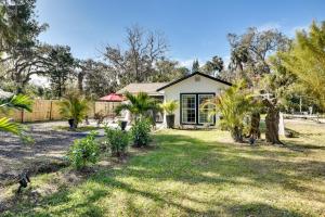 uma casa com um quintal com árvores e uma cerca em New Smyrna Beach Cottage about 1 Mi to Downtown! em New Smyrna Beach