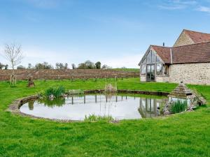 a pond in a field next to a house at Pears Cottage - Uk43674 in Beckington