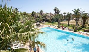 una grande piscina con persone in un resort di Villetta Parisi a Mazara del Vallo