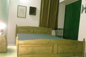 una camera con letto in legno con tenda verde di Villetta Parisi a Mazara del Vallo