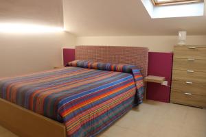 1 dormitorio con 1 cama con una manta a rayas de colores en Casa Vacanze "La Mansardina", en Ortona
