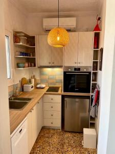 a kitchen with white cabinets and a yellow light fixture at Socratous House in Salamina +25 photos