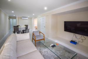a living room with a couch and a tv on a wall at 3 min walk to beach - Blue Waters Apt 2 apts in Bridgetown