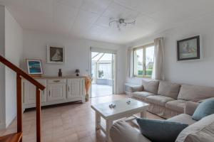 ein Wohnzimmer mit einem Sofa und einem Tisch in der Unterkunft La maison des dunes - Proche plage pour 6 in Courseulles-sur-Mer