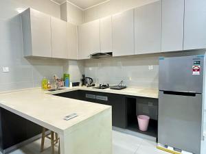 een keuken met witte kasten en een roestvrijstalen koelkast bij Danga Bay 4pax Highest floor Nice View in Johor Bahru +5 foto's