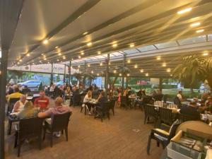 un grupo de personas sentadas en mesas en un restaurante en Hotel Restaurant Hellas, en Gelting