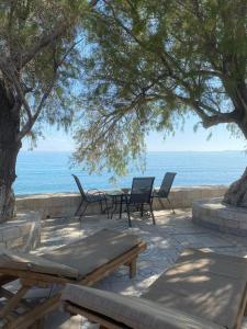 patio ze stołami i krzesłami nad oceanem w obiekcie House On The Wave w mieście Marathokampos