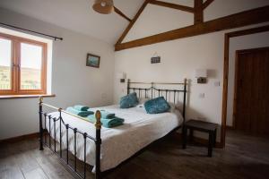 una camera da letto con un letto con cuscini blu e una finestra di 1 Beacon View Barn a Felindre