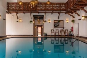 uma piscina interior com cadeiras e mesas num edifício em Spice Tree by Turaco em Zanzibar City