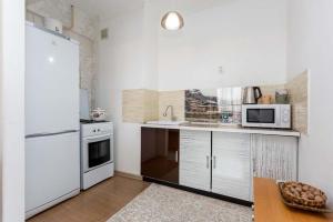 a kitchen with a white refrigerator and a microwave at Светлая квартира рядом с парком Горького in Almaty