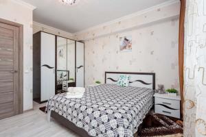 a bedroom with a bed with a black and white comforter at Светлая квартира рядом с парком Горького in Almaty