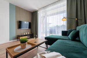 ein Wohnzimmer mit einem grünen Sofa und einem Tisch in der Unterkunft Apartament Mglisty Poranek - Laguna Beskidów - Dream Apart in Zarzecze