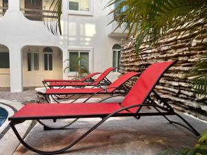 a row of red chairs sitting next to a building at Playakaan21 by Utopia in Playa del Carmen