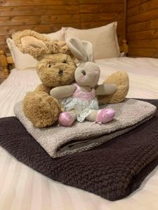 two stuffed rabbits sitting on a blanket on a bed at Вили Янкови in Dobri Dyal