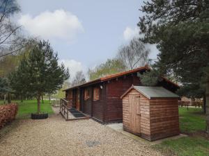 a small wooden cabin in a park with trees at Teal Lodge in Market Rasen