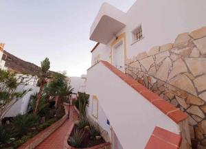 a white building with a staircase next to a stone wall at Apartamento Vista Atlántico in Adeje