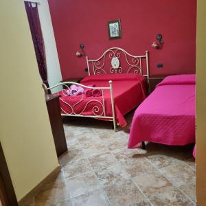 two beds in a room with pink walls at Stella Sulcitana in Gonnesa