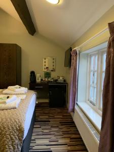 a bedroom with a bed and a desk and a window at George and Dragon in Tarvin