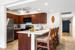 a kitchen with wooden cabinets and a kitchen island with chairs at Casa De Emdeko 104 in Kailua-Kona