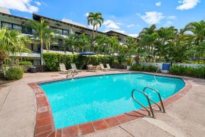 a swimming pool with chairs and a building at Casa De Emdeko 104 in Kailua-Kona